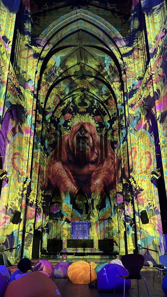 An orangutan sits in the middle of the building's grand archways, surrounded by floral patterns in rich yellows, light blues and reds.