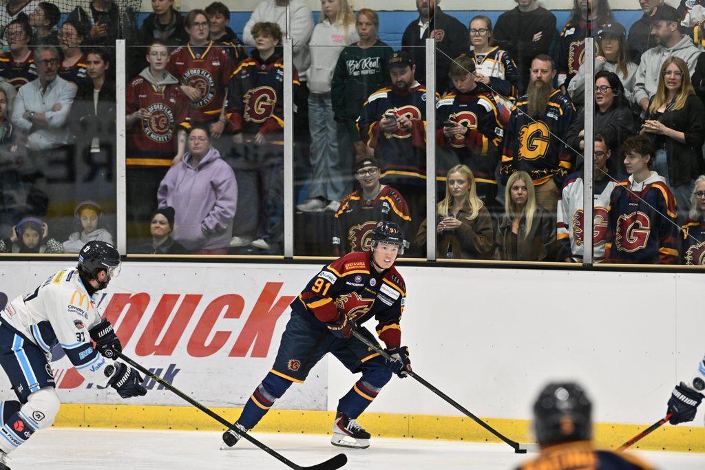 Guildford Flames player Joshua Waller on the ice against Coventry Blaze, with Guildford fans behind