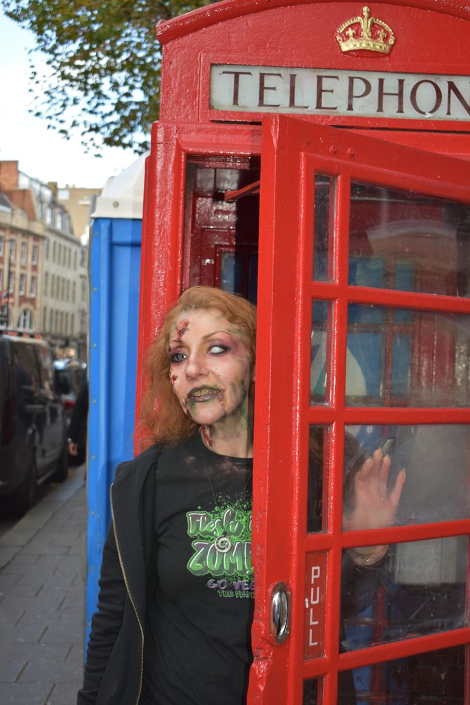 A zombie poses by a red telephone box