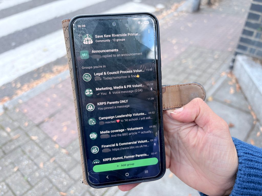 A photo of a mobile phone showing the WhatsApp community group set up to save Kew Riverside Primary School