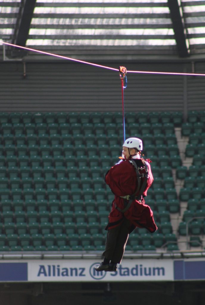 Matthew Wherry ziplining across the Allianz Stadium in Twickenham in his official robes and hard hat.