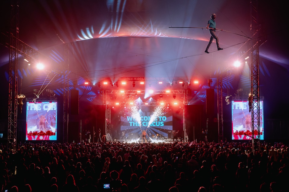 Tightrope performer above the stage and crowd at a Rock N Roll Circus event