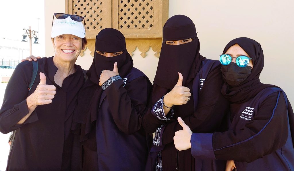 An image of Catherine DeVrye posing with three women in burkas while they all give a thumbs up for the camera.