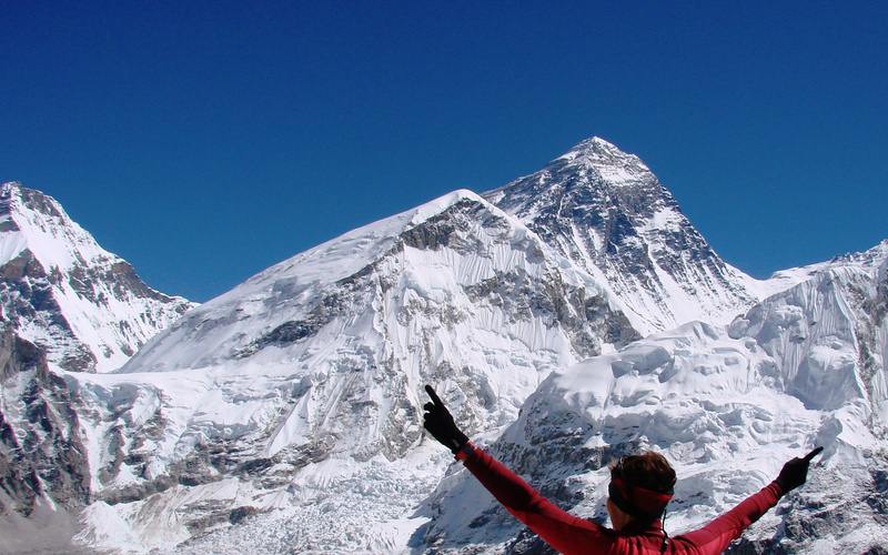 Catherine holding her arms outstretched looking up at the peak of Mount Everest