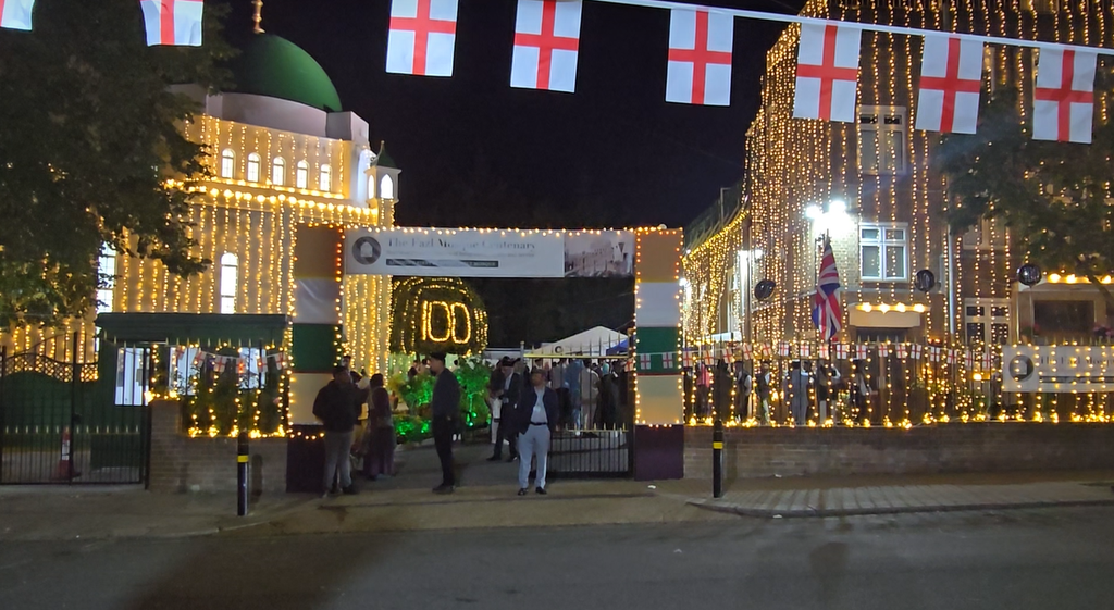 Fazal Mosque lit up, with the English flag and people talking to each other.